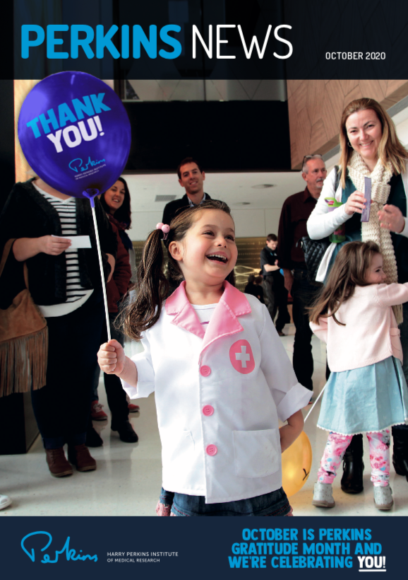 A young girl wearing a white and pink lab coat holding a baloon that says thank you.